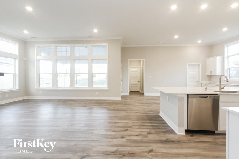 an open kitchen and living room with white walls and wood floors