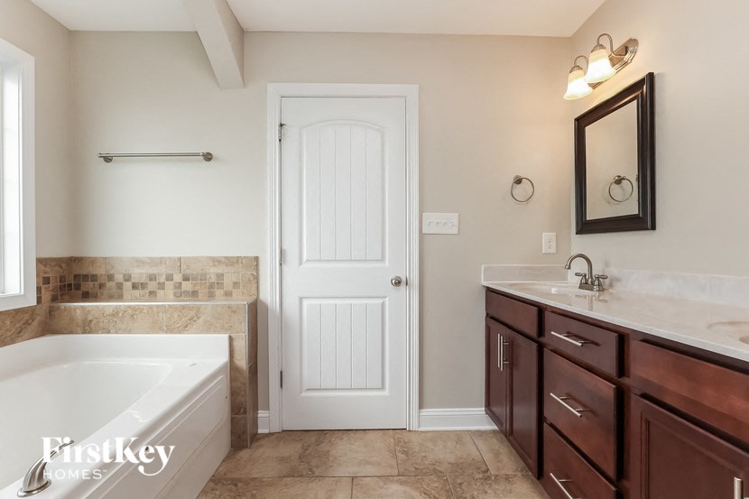 a bathroom with a tub and a sink and a white door