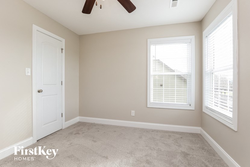 a empty room with a white door and two windows