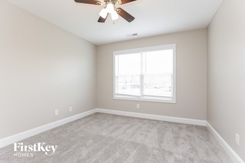 the living room of a new home with carpet and a ceiling fan