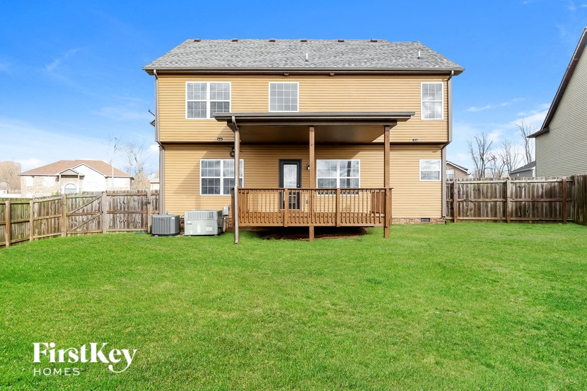 the back of a yellow house with a fenced in backyard