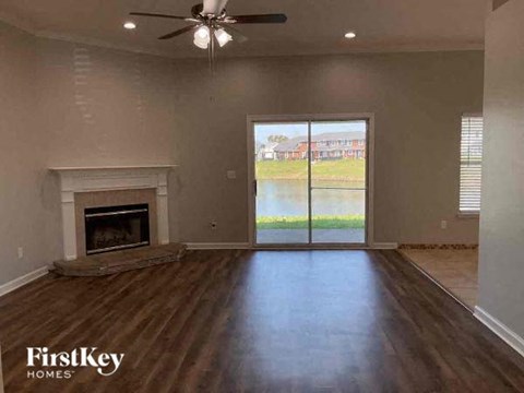 A spacious room with a fireplace and sliding glass doors leading to a view of a body of water.