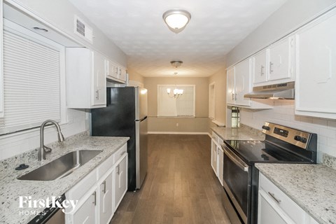 a kitchen with white cabinets and black appliances and counter tops