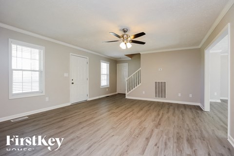 A spacious room with a wooden floor and a ceiling fan.