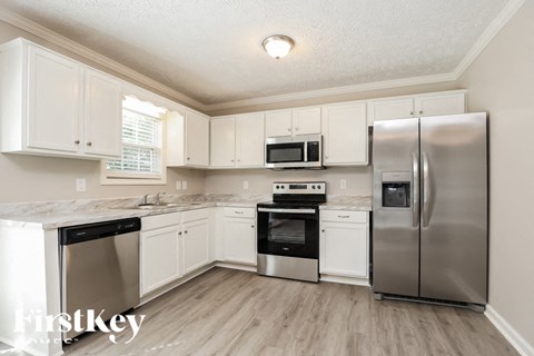 A kitchen with stainless steel appliances and white cabinets.