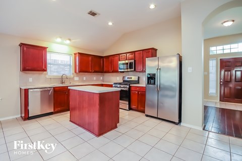 A kitchen with red cabinets and a white island.