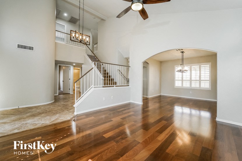 A spacious room with wooden floors and a staircase.