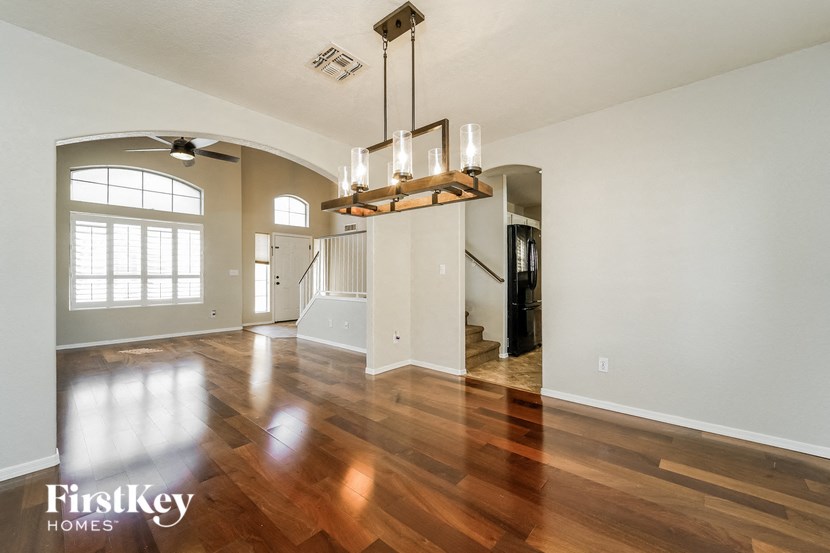 A large empty room with wooden floors and a chandelier hanging from the ceiling.
