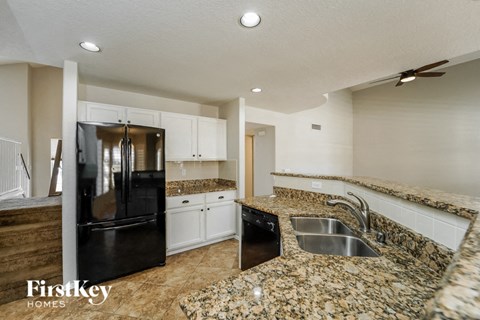 A kitchen with granite countertops and a black refrigerator.
