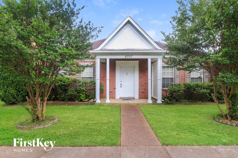 a small brick house with a white door and a lawn