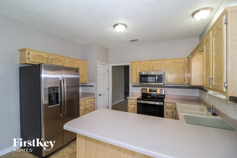a kitchen with wooden cabinets and stainless steel appliances and a white counter top