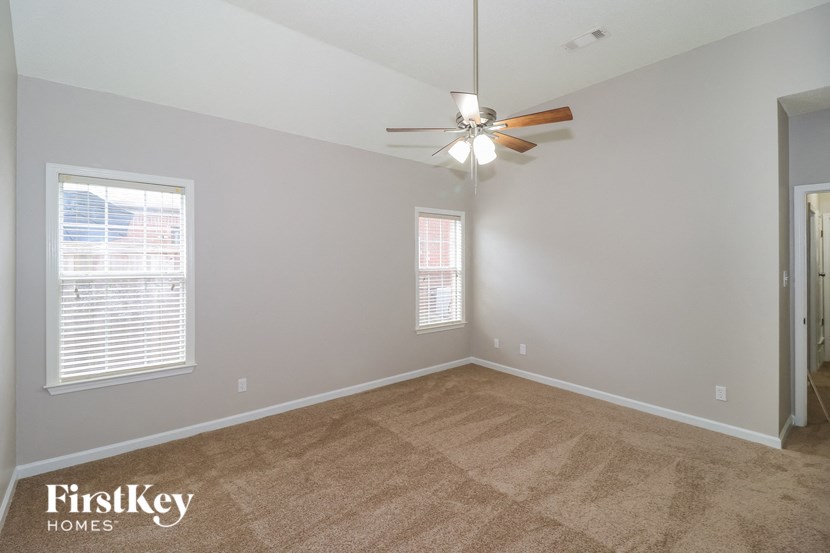 the living room of an empty house with carpet and a ceiling fan