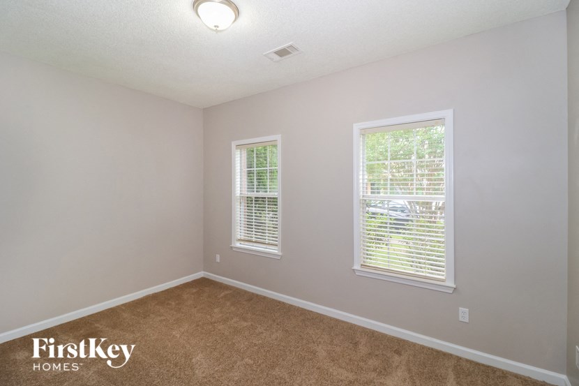 a bedroom with a carpeted floor and two windows