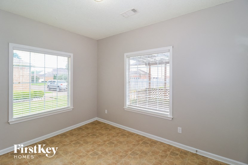 the living room of a home with two windows and a tiled floor