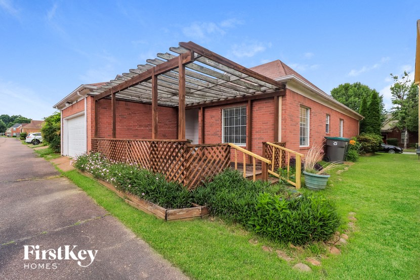 an old brick house with a porch and a wooden fence