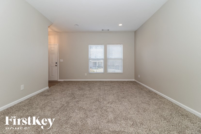 A room with a carpeted floor and a window with blinds.