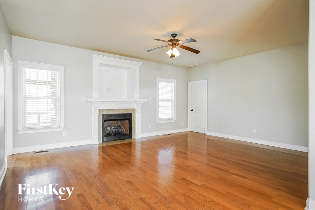 an empty living room with a ceiling fan and a fireplace