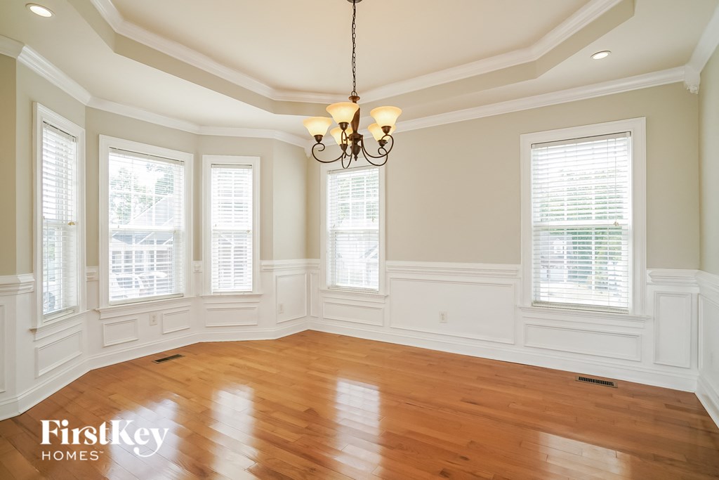 an empty dining room with wood floors and a chandelier