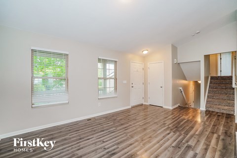 the living room and entryway of an empty house with wood flooring
