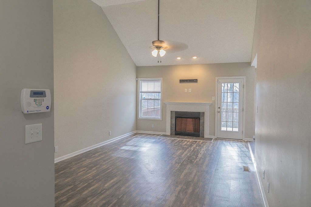 an empty living room with a fireplace and a ceiling fan