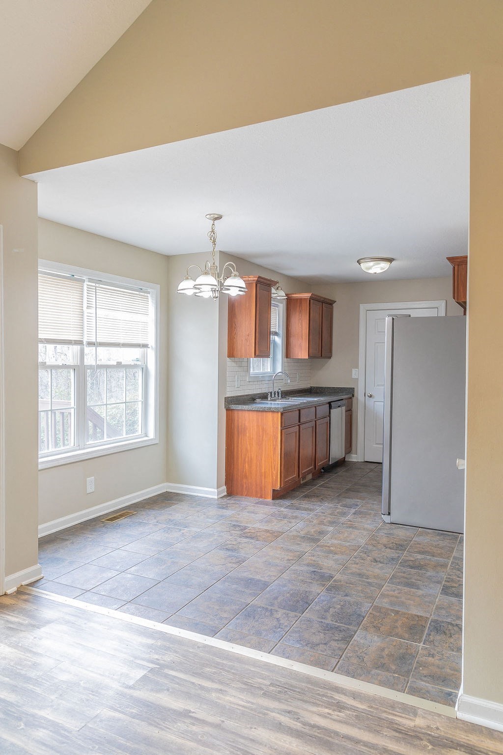 an empty kitchen with a refrigerator and a window