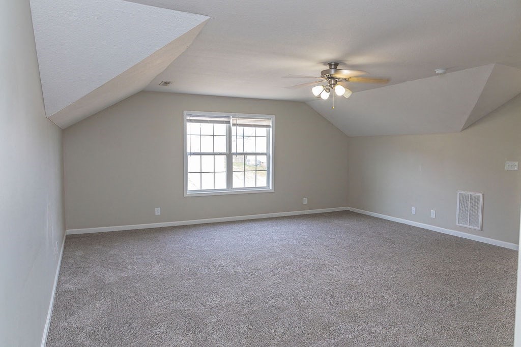 an empty bedroom with a ceiling fan and a window
