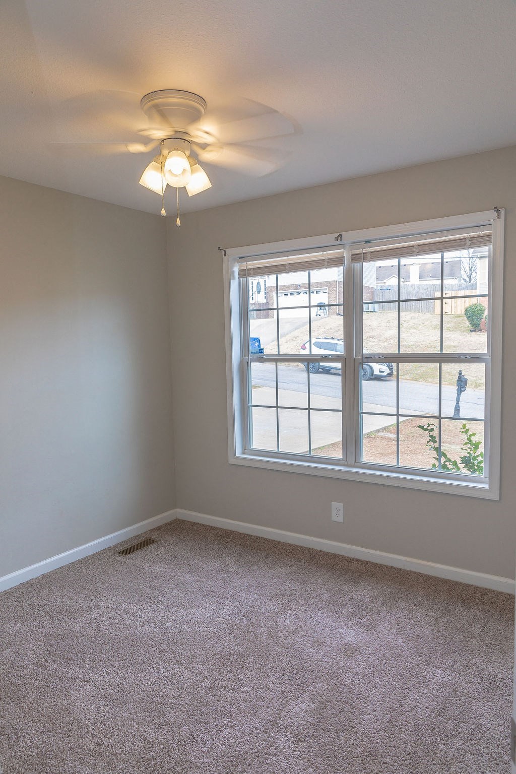 a bedroom with a large window and a ceiling fan
