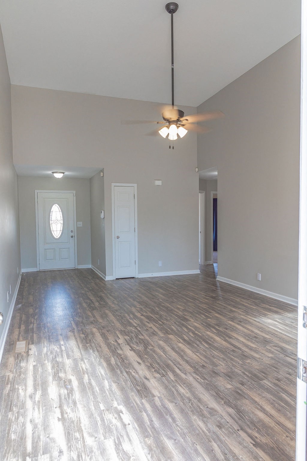 an empty living room with wood floors and a ceiling fan