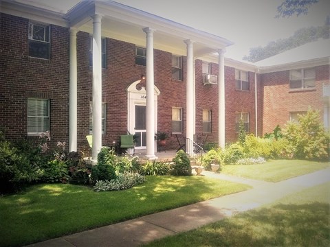 A red brick building with a porch and a white roof.