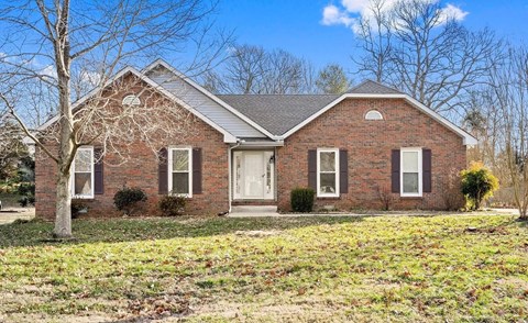 the front of a brick house with a grassy yard