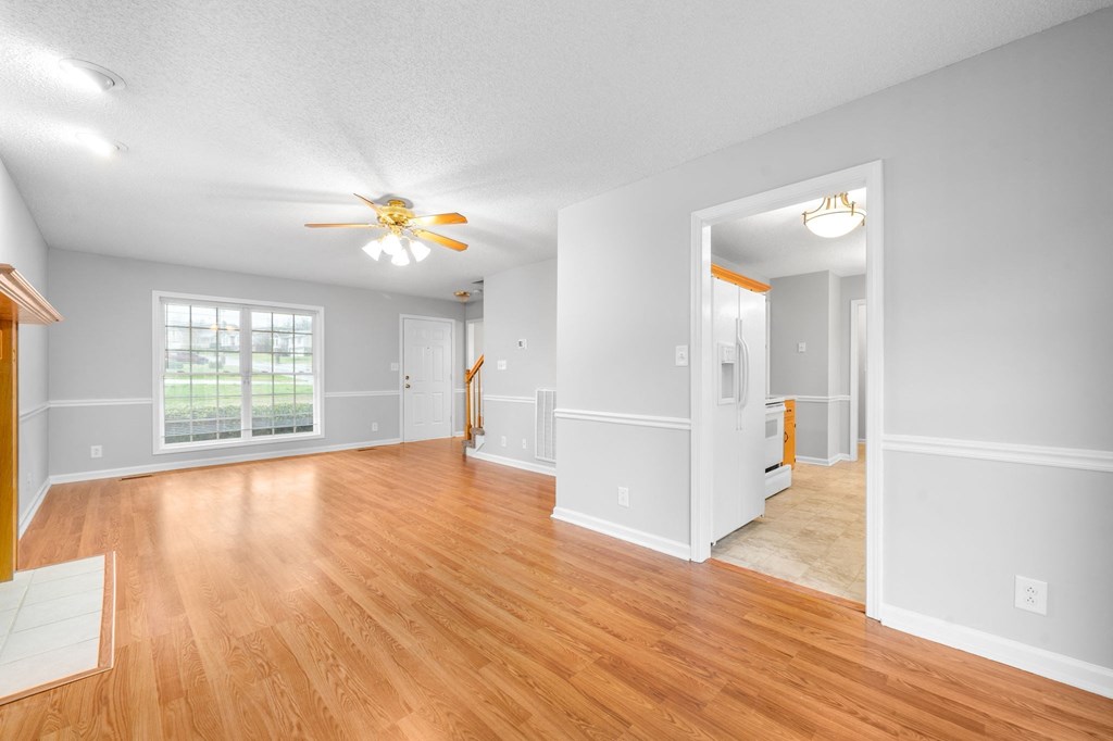 an empty living room with wood floors and a ceiling fan