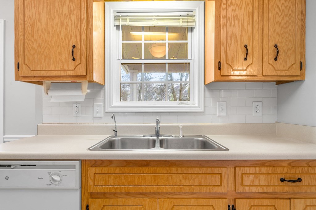 a kitchen with wooden cabinets and a window above a sink
