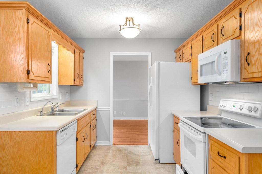 a kitchen with white appliances and wooden cabinets