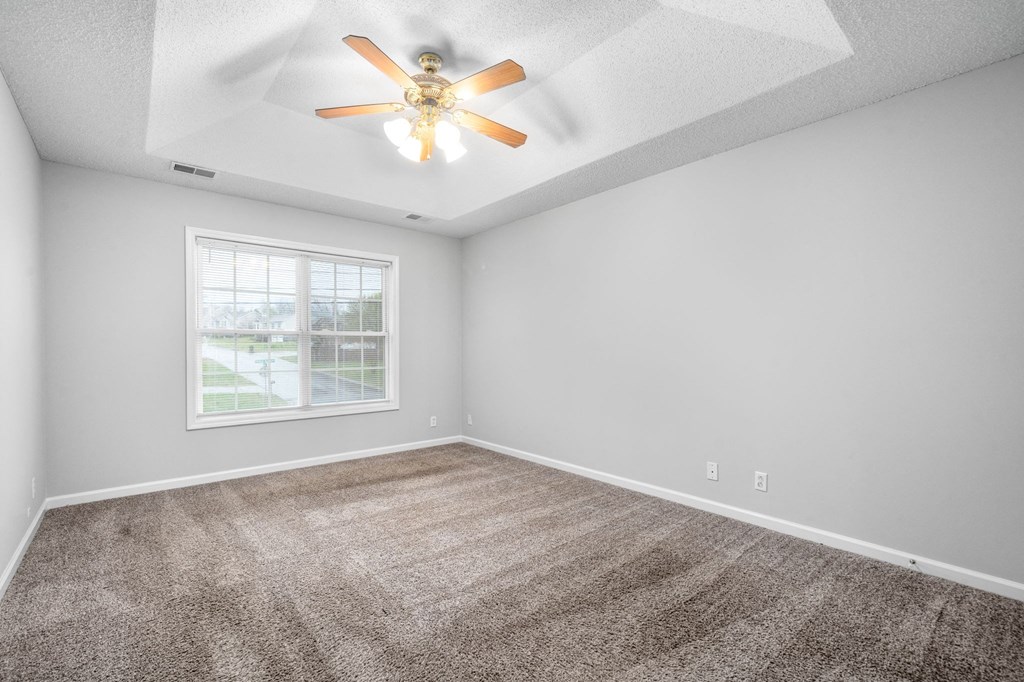 an empty living room with a ceiling fan and a window