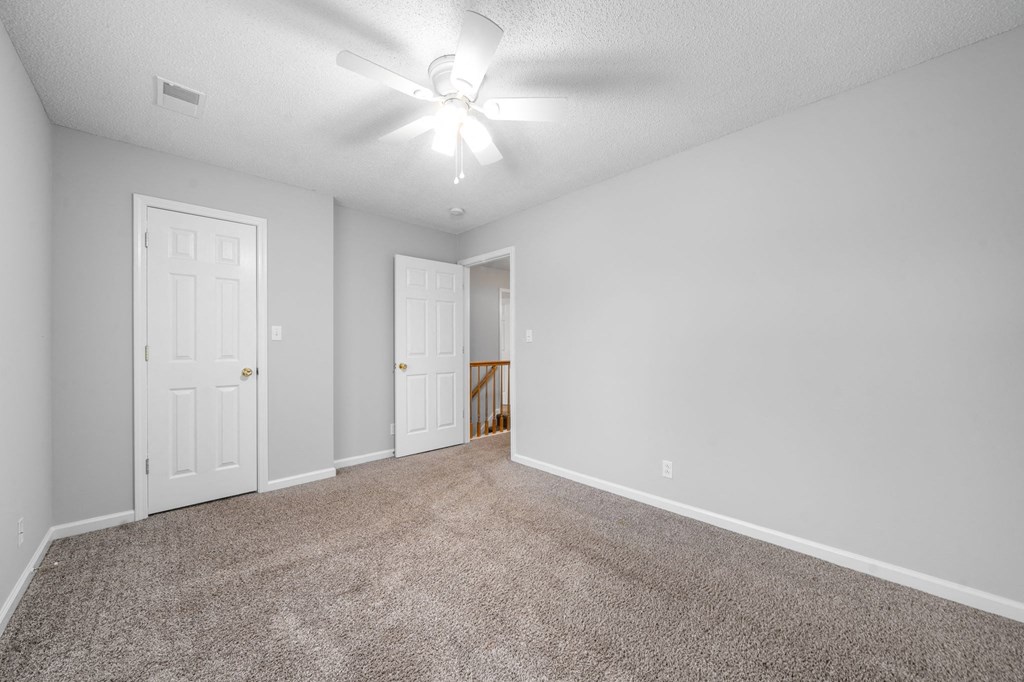 an empty living room with carpet and a ceiling fan