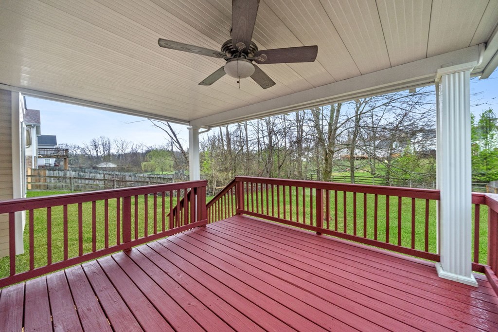 a porch with a red deck and a ceiling fan