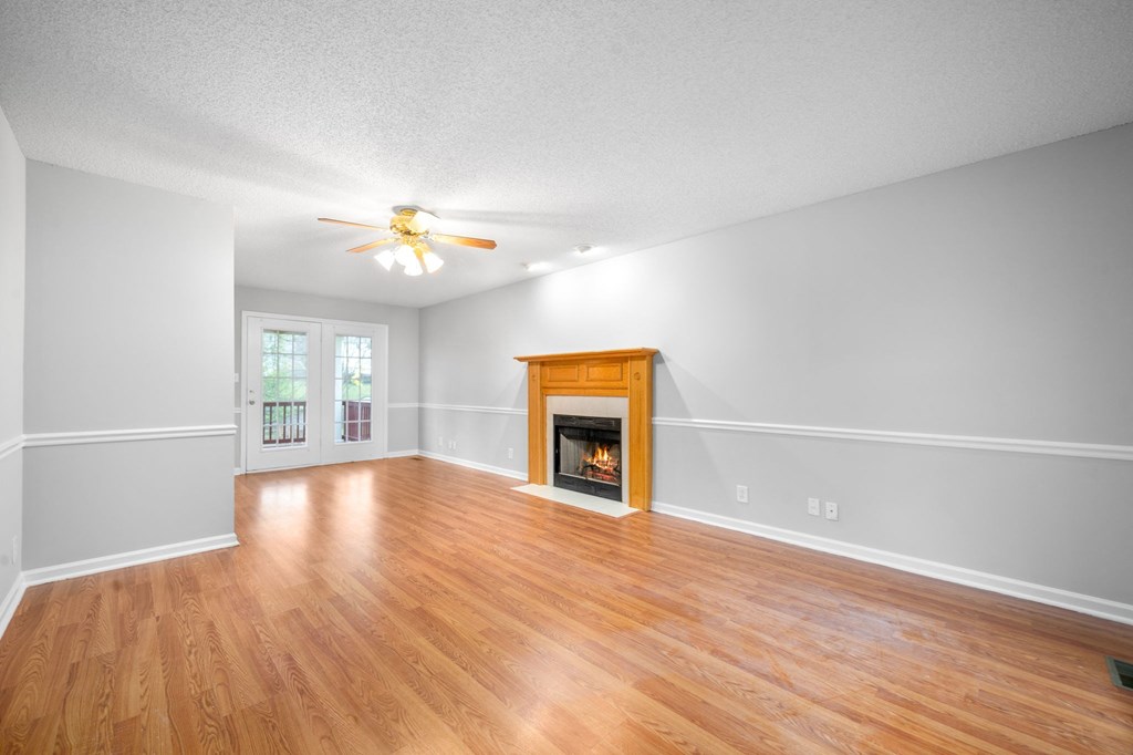 an empty living room with a fireplace and wooden floors