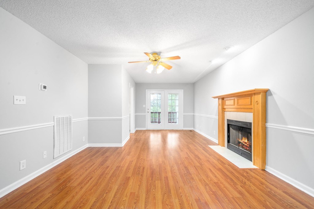 an empty living room with a fireplace and a ceiling fan