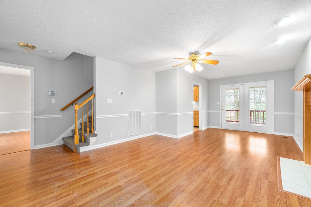 an empty living room with wood floors and a ceiling fan