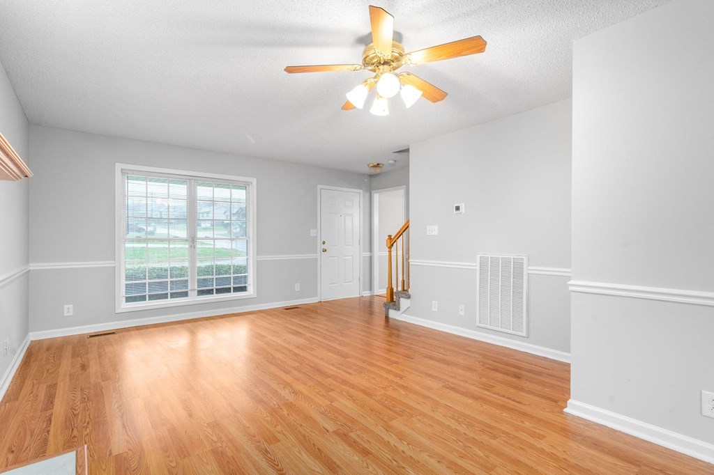 an empty living room with wood floors and a ceiling fan
