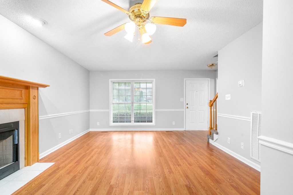 an empty living room with a fireplace and a ceiling fan