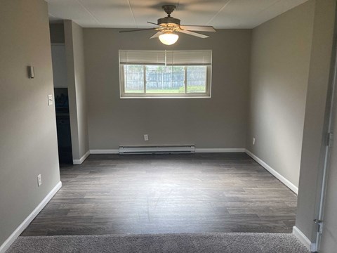 A room with a ceiling fan and a window with blinds.