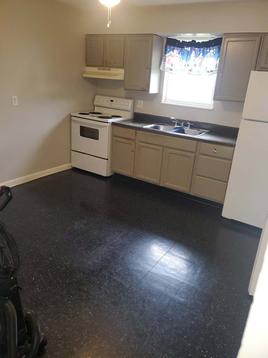 A kitchen with black flooring and white appliances.