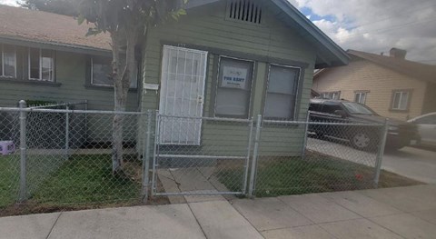 a green house with a fence in front of it