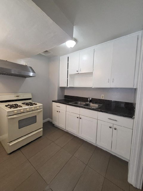 a kitchen with white cabinets and a stove and a sink