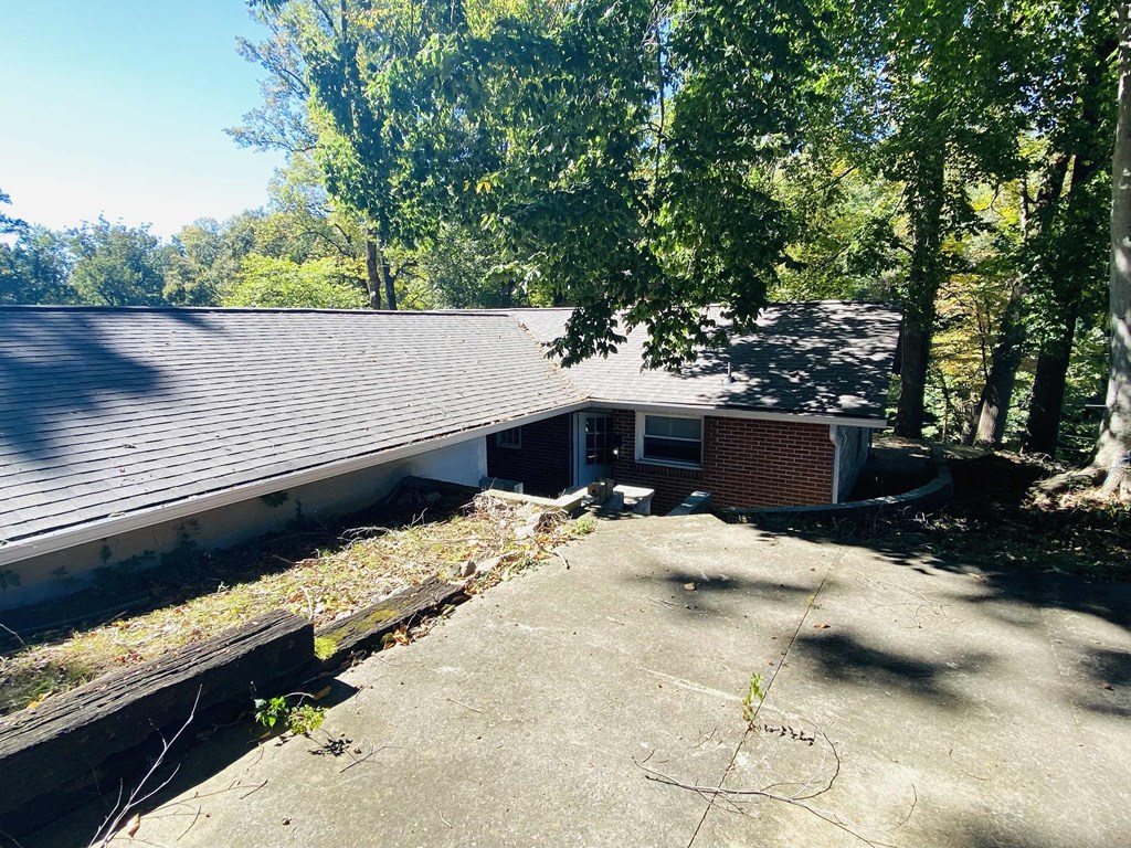 a view of the back of a house with a driveway and trees