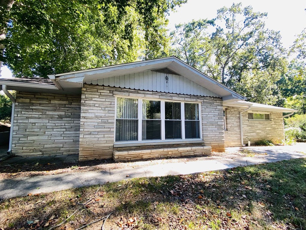 a small brick house with a sidewalk in front of it