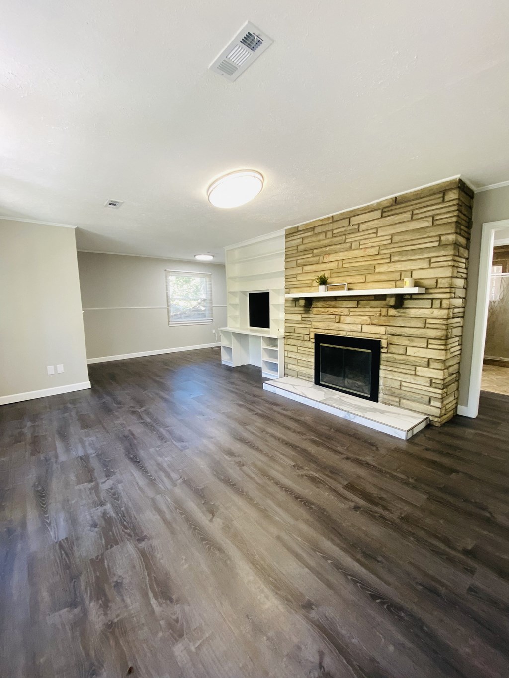 an empty living room with a fireplace and wooden floors