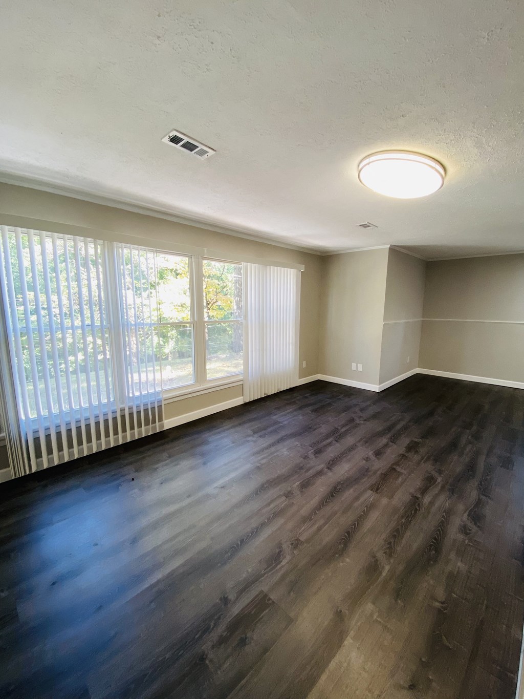 an empty living room with wood flooring and large windows