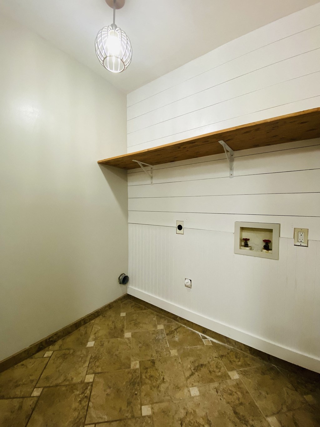 a small room with a white wall and a wooden shelf